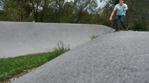 SLOW MOTION Young man speeding through an asphalt berm on a skateboard Stock Footage 118929563