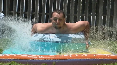 Slow motion: Young man splashes toward camera on inner tube. Stock Footage 40064225