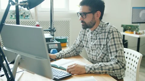 Slow motion of young man using computer and making 3d printer element Stock Footage 119568041
