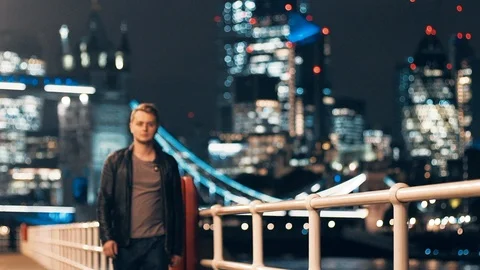 Slow motion young man walking alongside Thames River Tower Bridge at night Stock Footage 102860949
