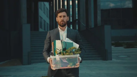 Slow motion young man walking with box of personal stuff at sunlight lose a job Stock Footage 129463087