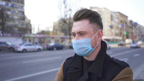 Slow motion. Young modern man in medical mask on city street with cars.  Stock Footage 130637135