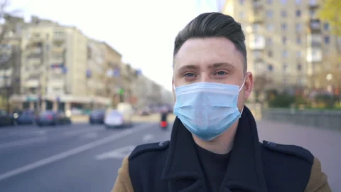 Slow motion. Young modern man in medical mask on city street with cars.  Stock Footage 130637140