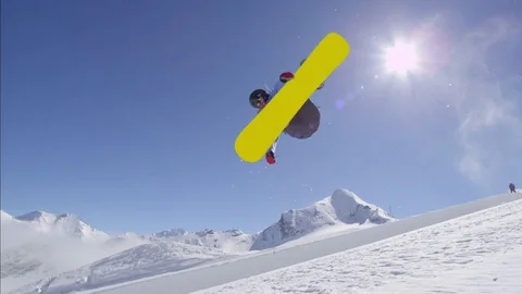 SLOW MOTION: Young pro snowboarder jumping over the sun in half pipe snow park Stock Footage
