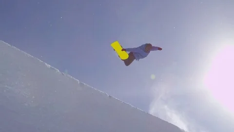 SLOW MOTION: Young pro snowboarder jumping in half pipe in sunny snow park Stock Footage 79548494