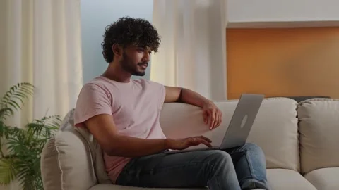 Slow motion young smiling man typing keyboard to send email on laptop. Funny Stock Footage 252609462