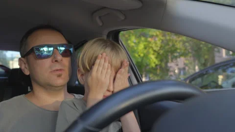 Slow motion. A young son is afraid while his father teaches him to drive a car Stock Footage 280599410