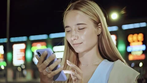 Slow motion young woman using phone smiling stand on street of night city typing Stock Footage 136846923