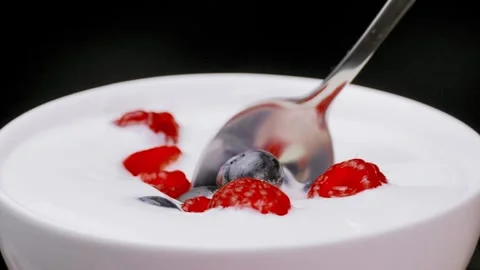 Slow motion of young woman's hand eating yogurt with spoon with berries Stock Footage 248779850