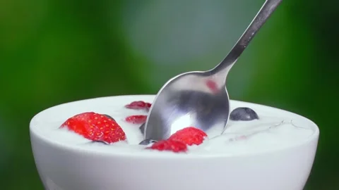 Slow motion of young woman's hand eating yogurt with spoon with berries 库存影片 248780555