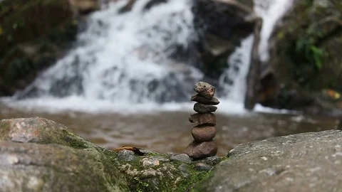 Slow-motion, zen stone balance in nature with waterfall background Stock Footage