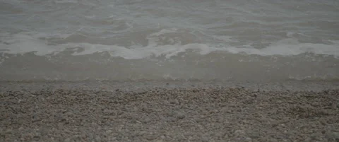 Slow Motion Zoom Out from Close-Up to Wide View of Waves on Shingle Beach Stock-Footage 320114872