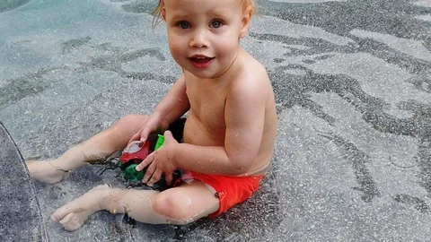 Slow motion.blonde boy of two years playing with a toy, sitting in the pool. Stock Footage 104698942