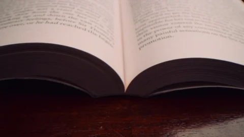 Slow move up the middle of an open book, skimming just above the surface Video stock 122604637