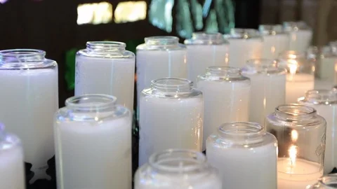 Slow move over white candles in church with one lit Video stock 107944003