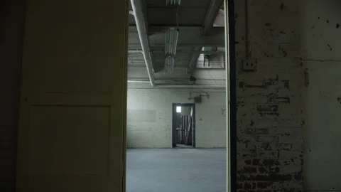 Slow move through door frame revealing a vacant warehouse 스톡 동영상 104437929