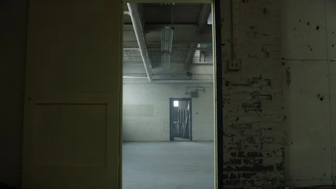 Slow move through door frame revealing a vacant warehouse Vídeos de archivo 104441187