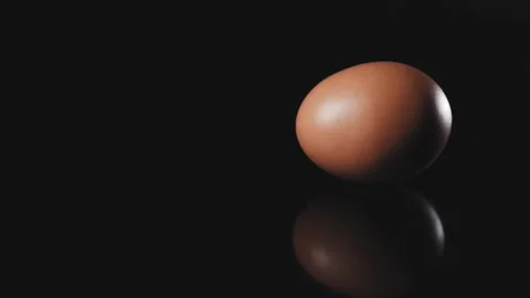 Slow movement of egg rotating in a circle on a dark table. Stock Footage 140247101