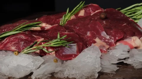 Slow movement shot along raw beef steaks with rosemary and spices on ice, Stock Footage 310337792