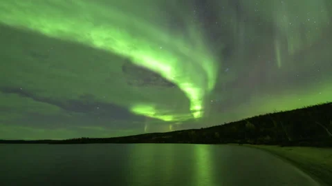 Slow moving aurora behind clouds in the sandy lake bay Stock Footage 250292886