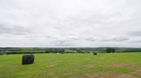 Slow moving clouds over wrapped hay bales in field Stock Footage 66777869