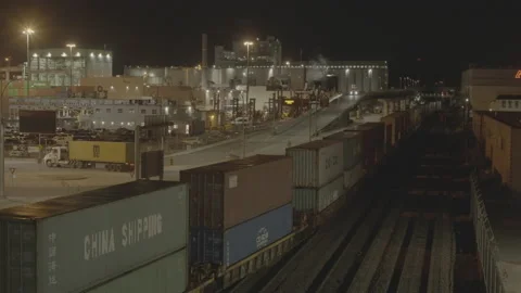Slow moving container train enters port as truck leaves Stock Footage 199455638