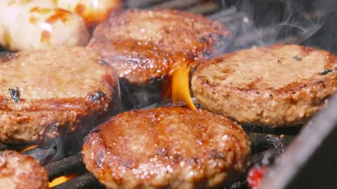 Slow Moving Shot Over BBQ with Juicy Beef Burgers Sizzling whilst being Flame Stock Footage 336495203