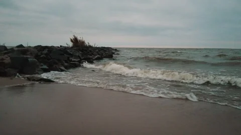 Slow moving shot of small waves crashing into the coast and the cribs. Stock Footage 256200104