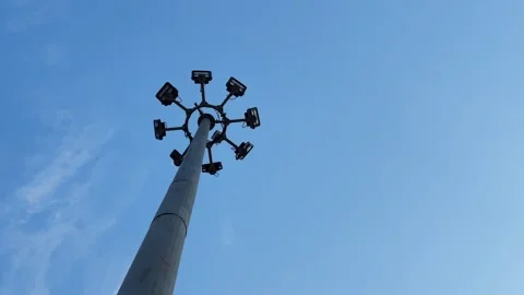 Slow Orbit Around High Mast Lighting Pole with Floodlights Against Clear Blue Stock Footage 340183488