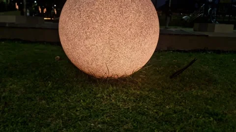 Slow Orbital Pan of Glowing Spherical Smart Lantern on Grassy Lawn Video stock 333021293