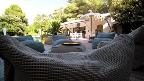 Slow orbiting shot around comfortable seating in a villas garden with a Stock Footage 285390812