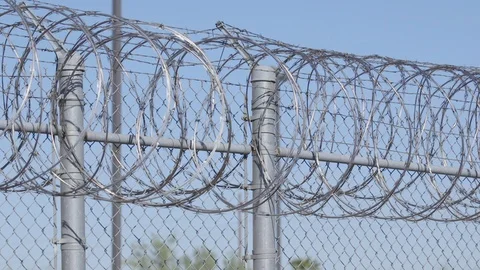 Slow pan across a barbwire fence outside an american jail Stock Footage 127987751