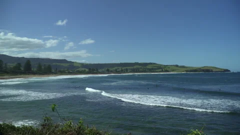 Slow Pan Across Pacific Ocean Bay with Surfers and Blue Sky Stock Footage 314313705