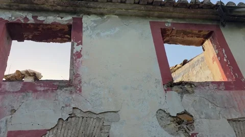 Slow pan along second floor facade of ruined abandoned house showing empty w Stock Footage 343797188