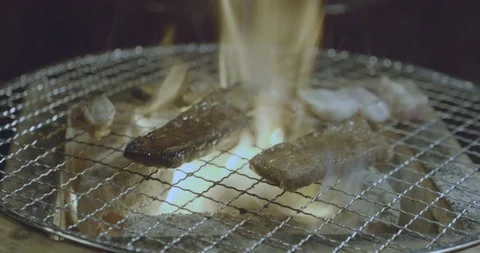 Slow pan around thinly sliced Japanese wagyu beef sizzling on a bbq charcoal Stock-Footage 115571587