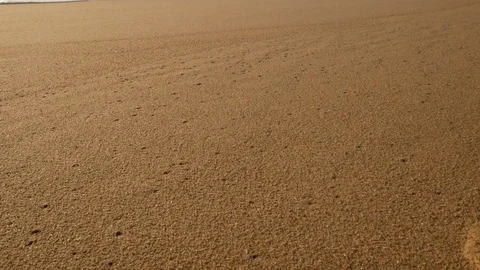 Slow pan up on beach from sand to waves breaking on shore Stock Footage 103289826