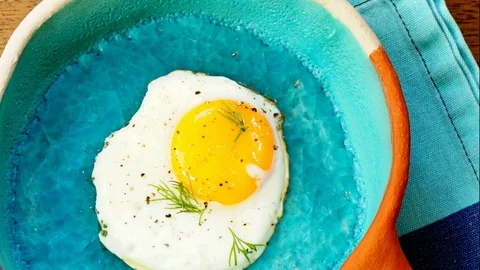 Slow pan on cooked egg in a blue ceramic pan. Video stock 104354180