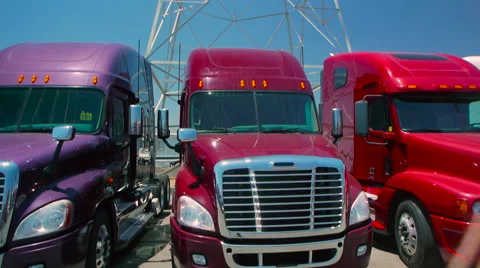 Slow pan down from electric tower to three freight liner trucks parked outdoors 스톡 동영상 60031141