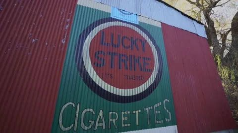 Slow pan down of Lucky Strikes sign painted on the wall of an old barn Stock Footage 147738329
