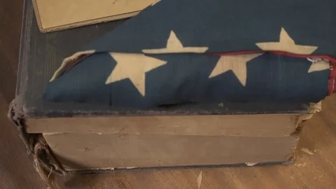 Slow pan of old US flag and unknown photo Stock Footage 98100302