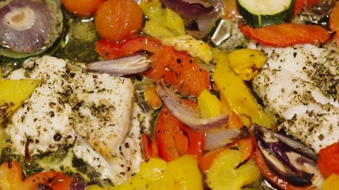 Slow pan over cooked traybake of wild caught atlantic Cod fillets in bubbling Vidéo 331275797