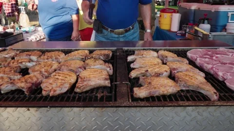 Slow pan over multiple pork chops on large open flame grill Stock Footage 239117651