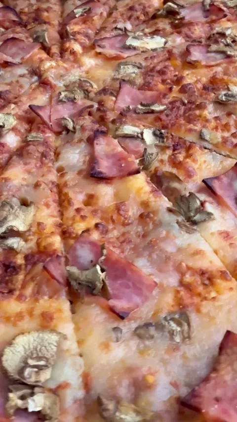 Slow pan over a pizza with ham and mushrooms Video stock 331981780