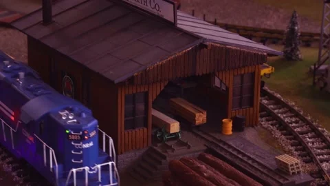 Slow pan over toy train set lumberyard to reveal blue locomotive Stock Footage