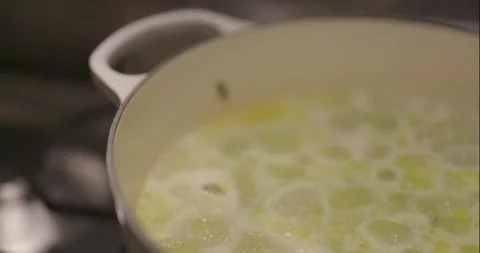 Slow pan right and down across a pot of simmering soup on a stove Stock Footage 261902193