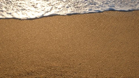 Slow pan up on sandy beach at sunset to ocean Stock Footage 100521409