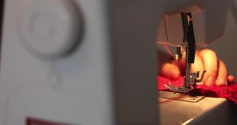 Slow pan from thread spool to sewing needle on machine with red fabric Stock Footage 98516593