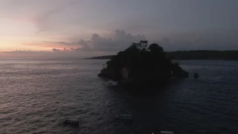 Slow pan up towards small island off the coast of Nusa Penida, Bali during sunse Stock Footage 223265099