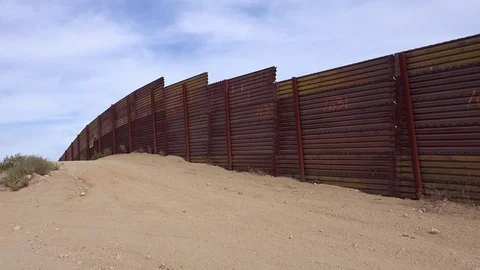 Slow pan of the U.S. Mexico border wall fence which ends suddenly in the desert Stock-Footage 79502130