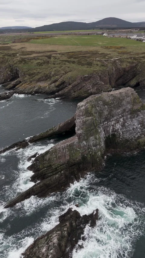 Slow panning drone shot of Bow Fiddle Rock sea arch in Scotland. Vertical Stock Footage 334951300